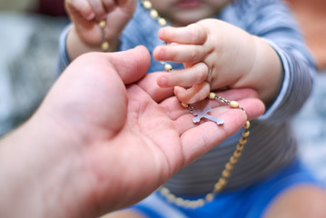 A child takes a rosary from his dad's hand