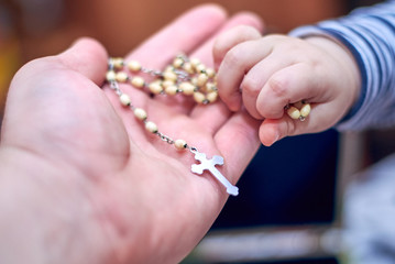 A child takes a rosary from his dad's hand