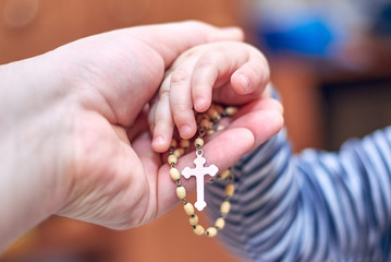 A child takes a rosary from his dad's hand