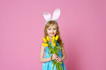 Obraz na płótnie Canvas Cute little girl in the form of an Easter Bunny with a bouquet of yellow tulips. concept of holidays, fashion and beauty. Happy Easter! Selective focus.