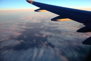 Fototapeta premium Clouds and wing of the plane on a clear morning