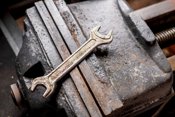 Old vintage spanner on a big iron vice isolated