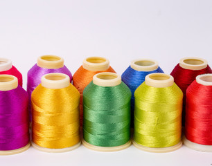 Colored thread coils on white background, sewing, place for text