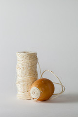 Oeuf en cours de décoration avec de la ficelle sur une bobine