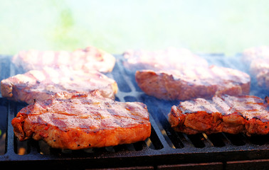 Steaks are grilled. White fragrant smoke above them.