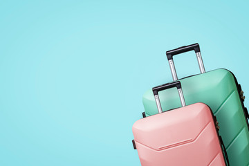 Fototapeta premium Two Suitcases on wheels on a blue background. Concept of travel, a vacation trip, a visit to relatives. Pink and Green color