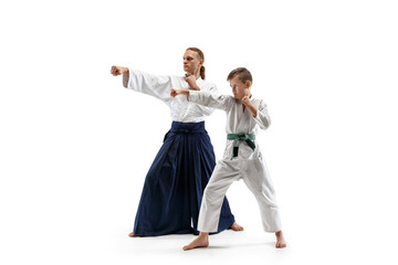 Man and teen boy fighting at Aikido training in martial arts school. Healthy lifestyle and sports concept. Fightrers in white kimono on white background. Karate men with concentrated faces in uniform.