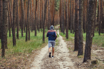 Obraz premium Man in a hoodie running in a pine forest. Concept of training in outdoor