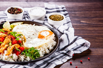 Grilled chicken meat with rice and fried egg on wooden table