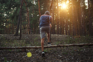 Man is engaged in running with obstacles in a pine forest. A beautiful play of light. Concept of...