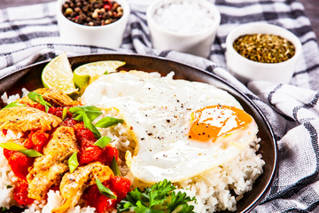 Grilled chicken meat with rice and fried egg on wooden table