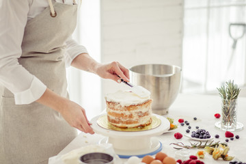 girl putting whipped cream on cake layers. close up side view photo. copy space