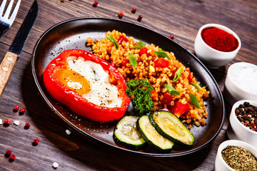 Fried egg, groats and vegetables on wooden table