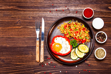 Fried egg, groats and vegetables on wooden table