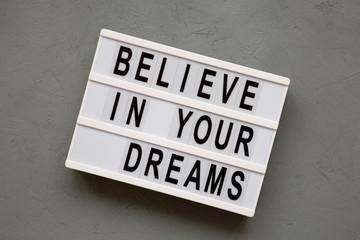 'Believe in your dreams' words on modern board over concrete background. From above, overhead, flat lay. Close-up.