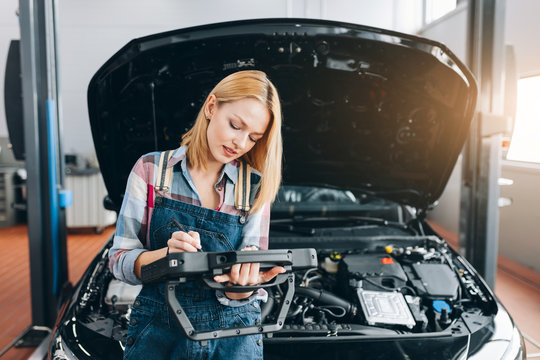 beautiful blond girl concentrated on working with digital tablet PC at the repair shop. close up photo. copy space. fast diagnostic