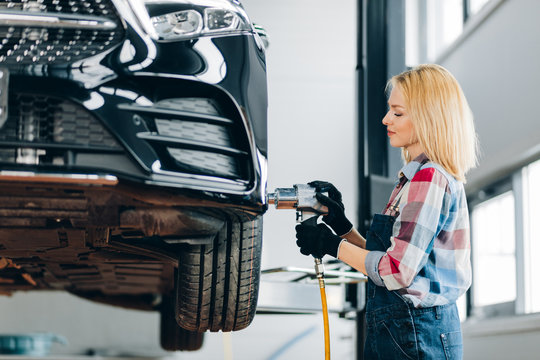 blond girl screwing car wheel at the garage. close up side view photo. working day