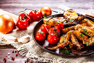 Roast chicken wings, baked potatoes and vegetables