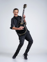 Naklejka premium Fifteen years old guitarist with a black electric guitar. Teenage musician holds guitar