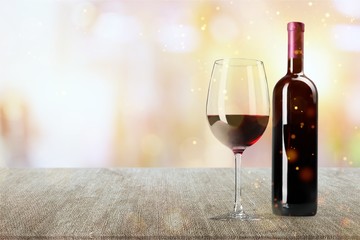 Red wine glass on wooden desk at wall background
