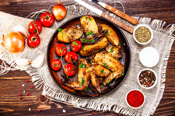 Roast chicken wings, baked potatoes and vegetables