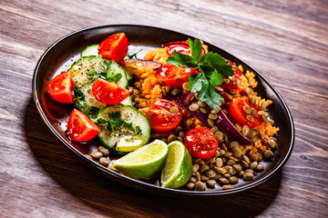 Groats with lentils and vegetables on wooden table