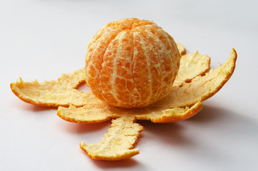ripe, juicy, peeled mandarin lies on the peel, on a white background