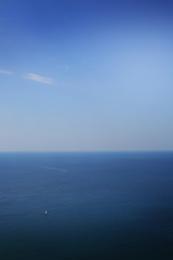 White sail on a background of blue sea from a height