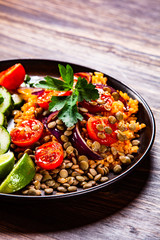 Groats with lentils and vegetables on wooden table