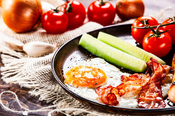 Breakfast - fried egg ,toasts,bacon, and vegetables