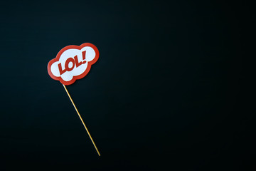 The inscription LOL. Sign on a stick on black background. Fool's day celebration concept.