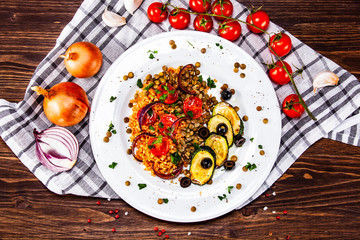 Groats with lentils and vegetables on wooden table