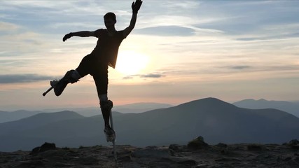 4k slow motion - man on the stilts jumps on one leg on the top of mountain.