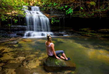 Woman at waterfall and swimming hole in bushland wilderness