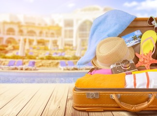 Retro suitcase with travel objects on wooden board on background