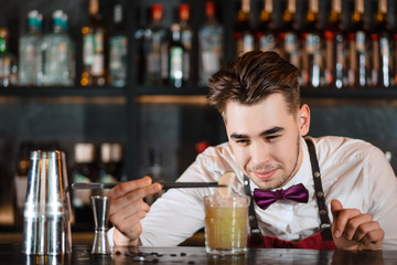 Professional bartender preparing a refreshing cocktail decorating it with a slice of lime.
