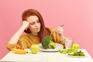 Red-haired frustrated confused disgusted displeased female model covering mouth with palms do not...