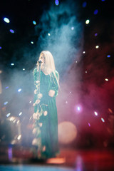 Young blond woman singer in concert light