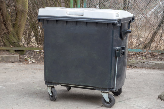 Large garbage container, trash dumpster and bin on a backyard. Orderly stowed garbage cans ready for separate garbage collection. Environmentally friendly trash container, recycle bin, tank.