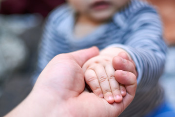 Dad is holding the hand of his son