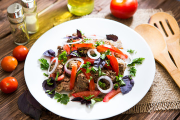 Fried liver with onion and tomatoes on wooden background
