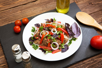 Fried liver with onion and tomatoes on black stone background