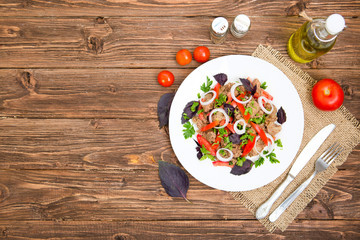 Fried liver with onion and tomatoes on wooden background