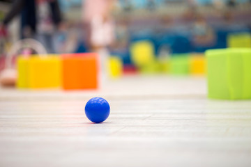 The blue plastic ball lies on a floor in the children's game room against the background of toys