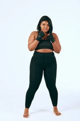 Fototapeta na wymiar Plump woman in black sports clothes exercising, showing her determination to loss weight. Isolated studio shot on white.