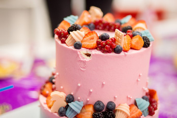 Beautiful pink festive cake costs on a table. Otkusan a small piece from cake. A sting on cake