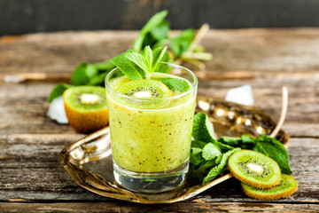 Glass of kiwi smoothie with fresh fruits on a wooden table