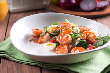 Healthy salad. Recipe for fresh seafood. Grilled shrimp, fresh vegetable salad and egg. Shrimp on the grill. Health food. Wooden background