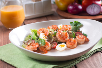 Healthy salad. Recipe for fresh seafood. Grilled shrimp, fresh vegetable salad and egg. Shrimp on the grill. Health food. Wooden background