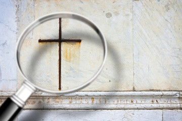 Looking for faith - concept image with a magnifying glass in front of a Christian cross